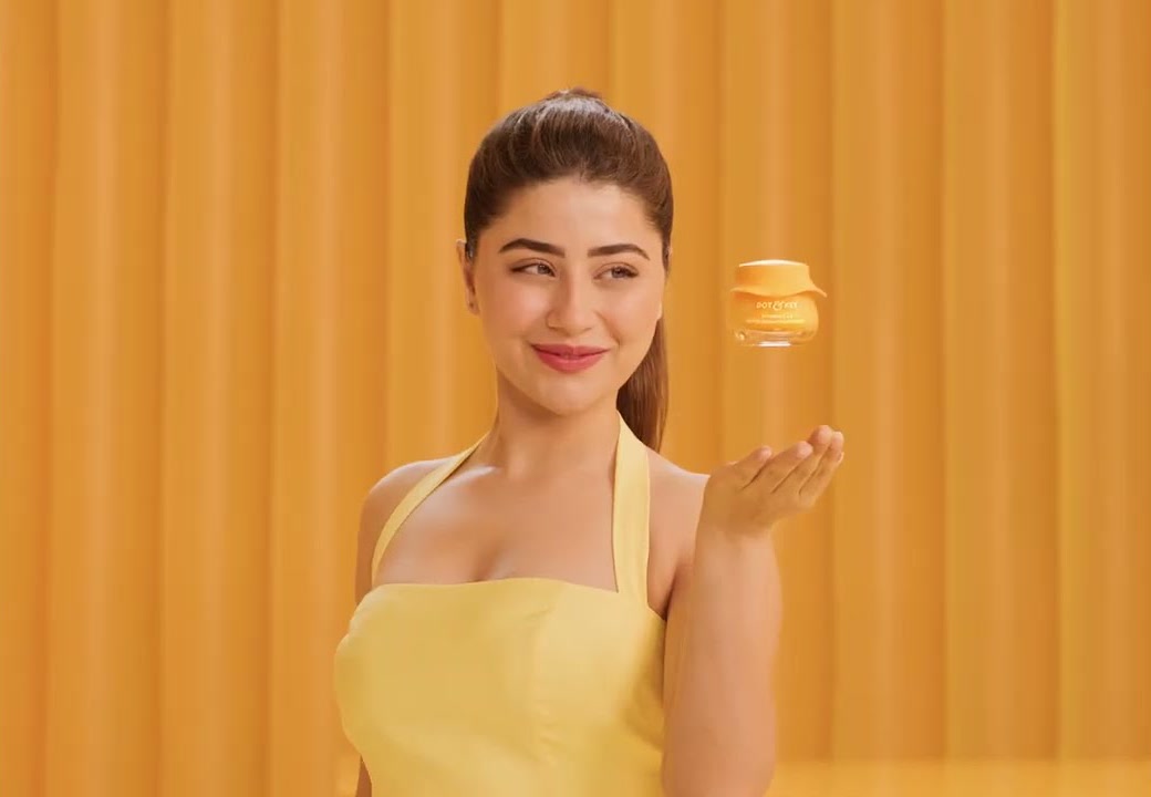 A woman glances at a floating moisturiser jar against a warm amber backdrop